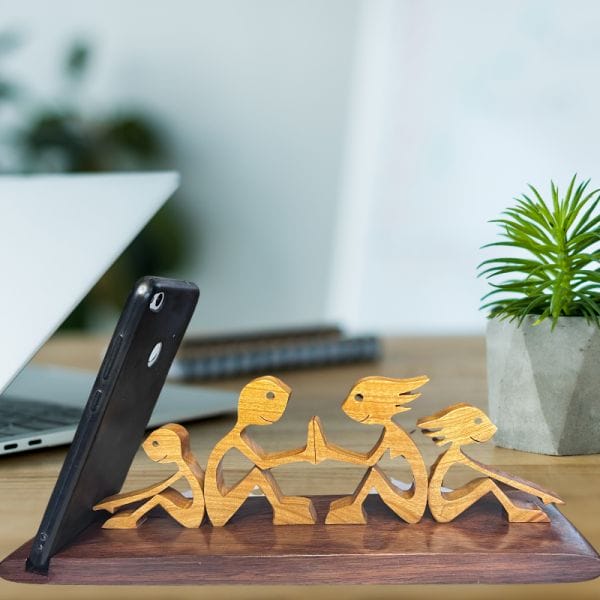 Fából készült telefontartó figura az asztalon.